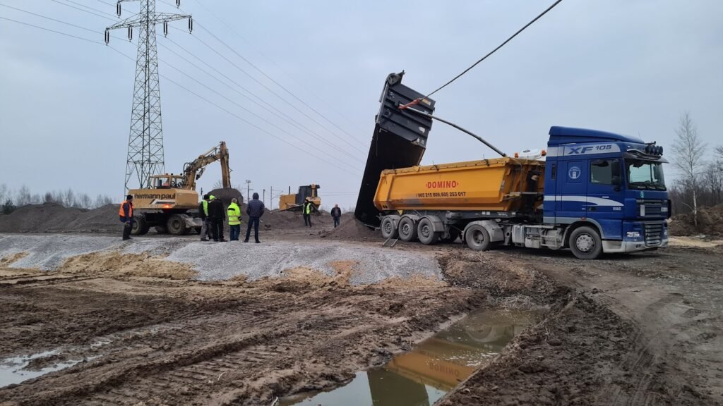 Samochód holowany przez pomoc drogową w Kątach Wrocławskich na tle malowniczego krajobrazu.